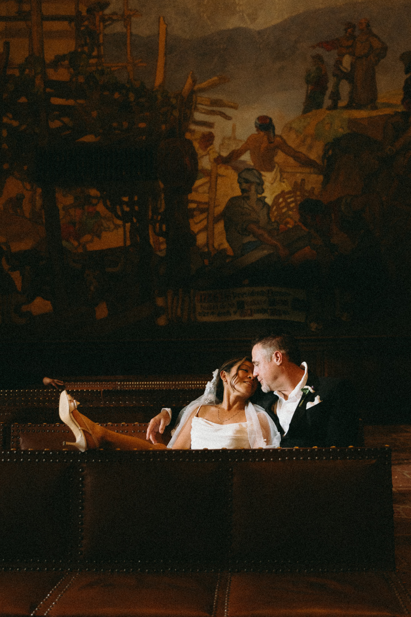 The newlyweds sitting together beneath a mural