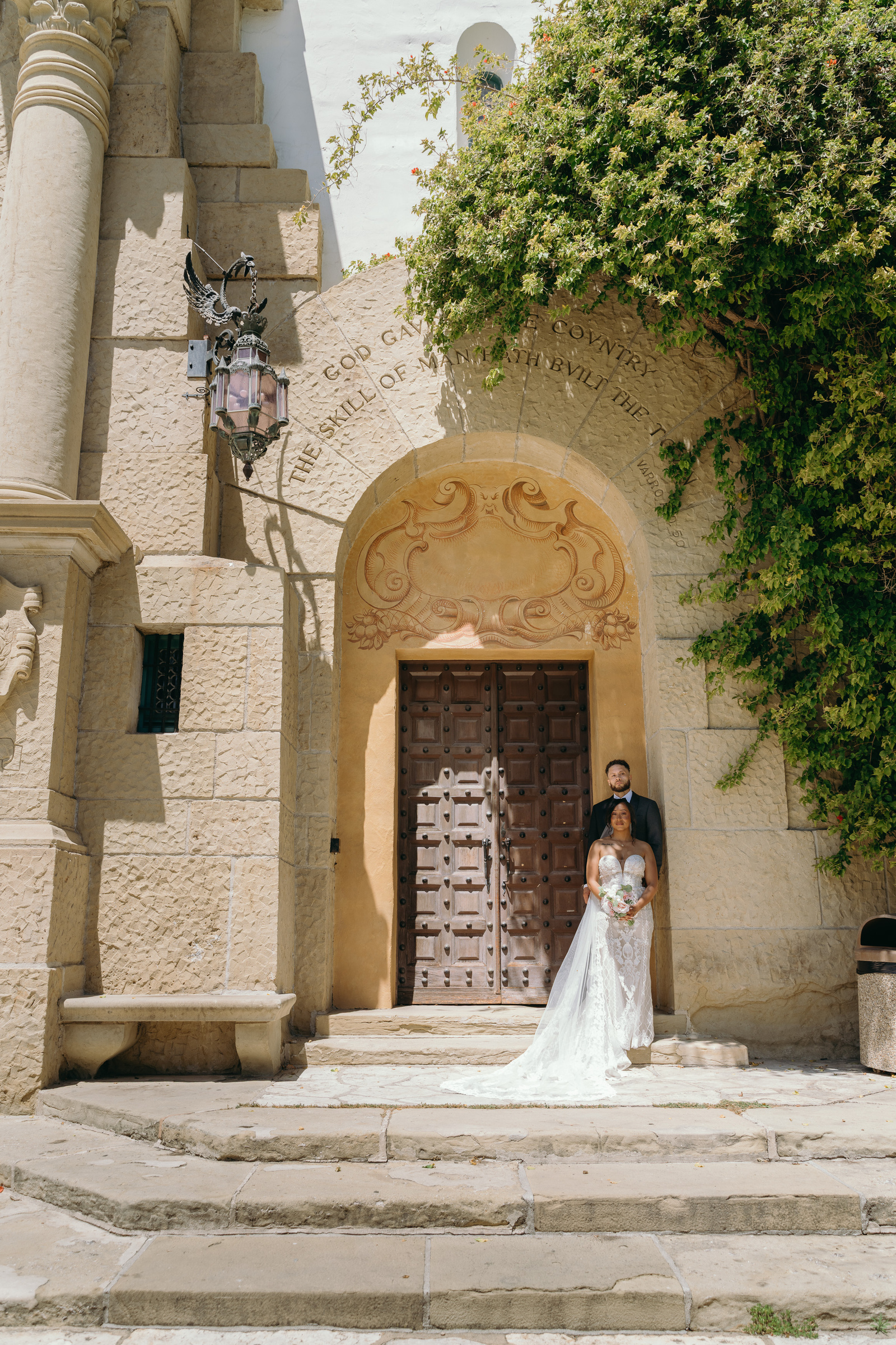 A wedding couple beneath a courtyard arch