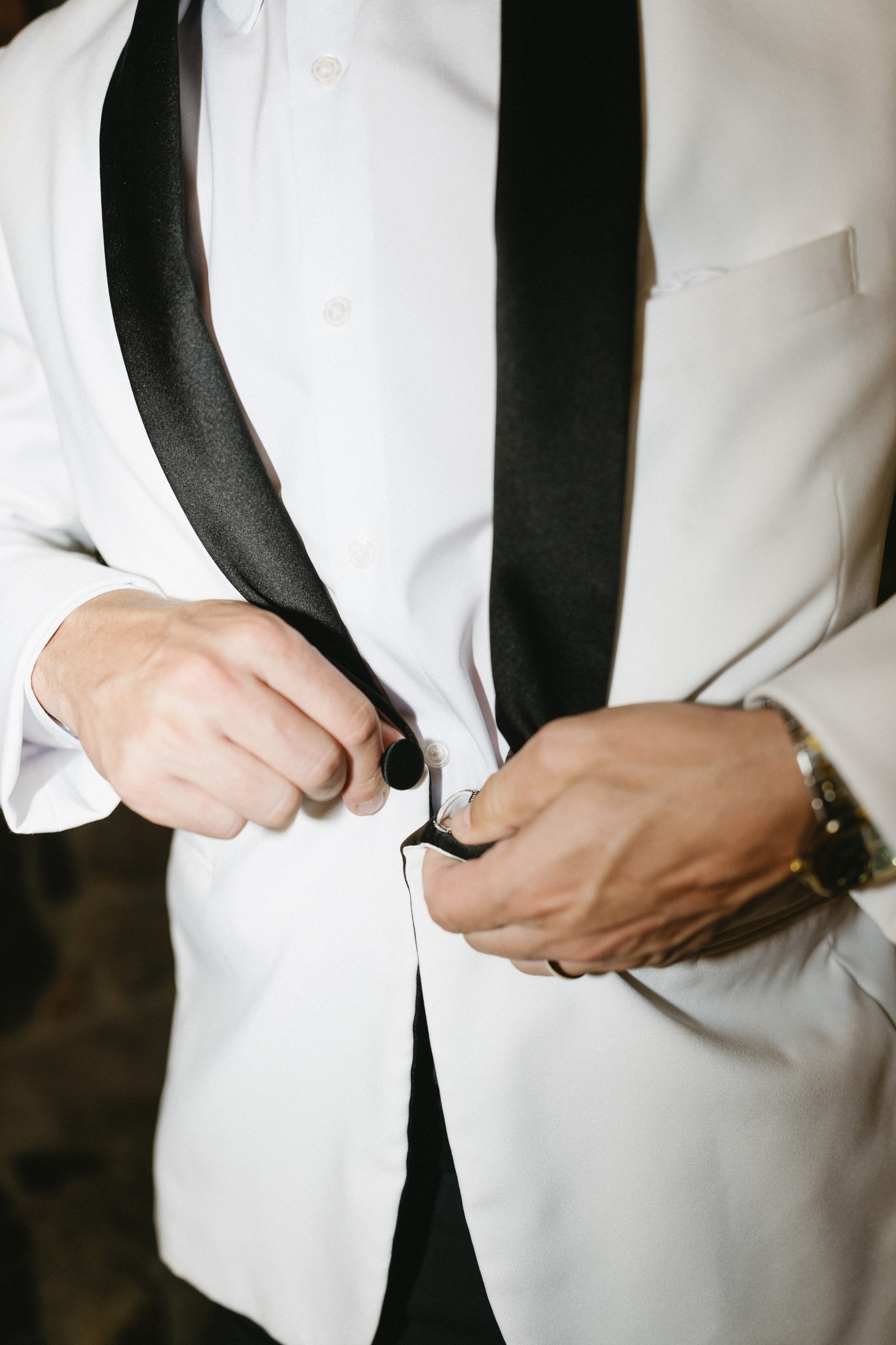 The groom fastening his dinner jacket