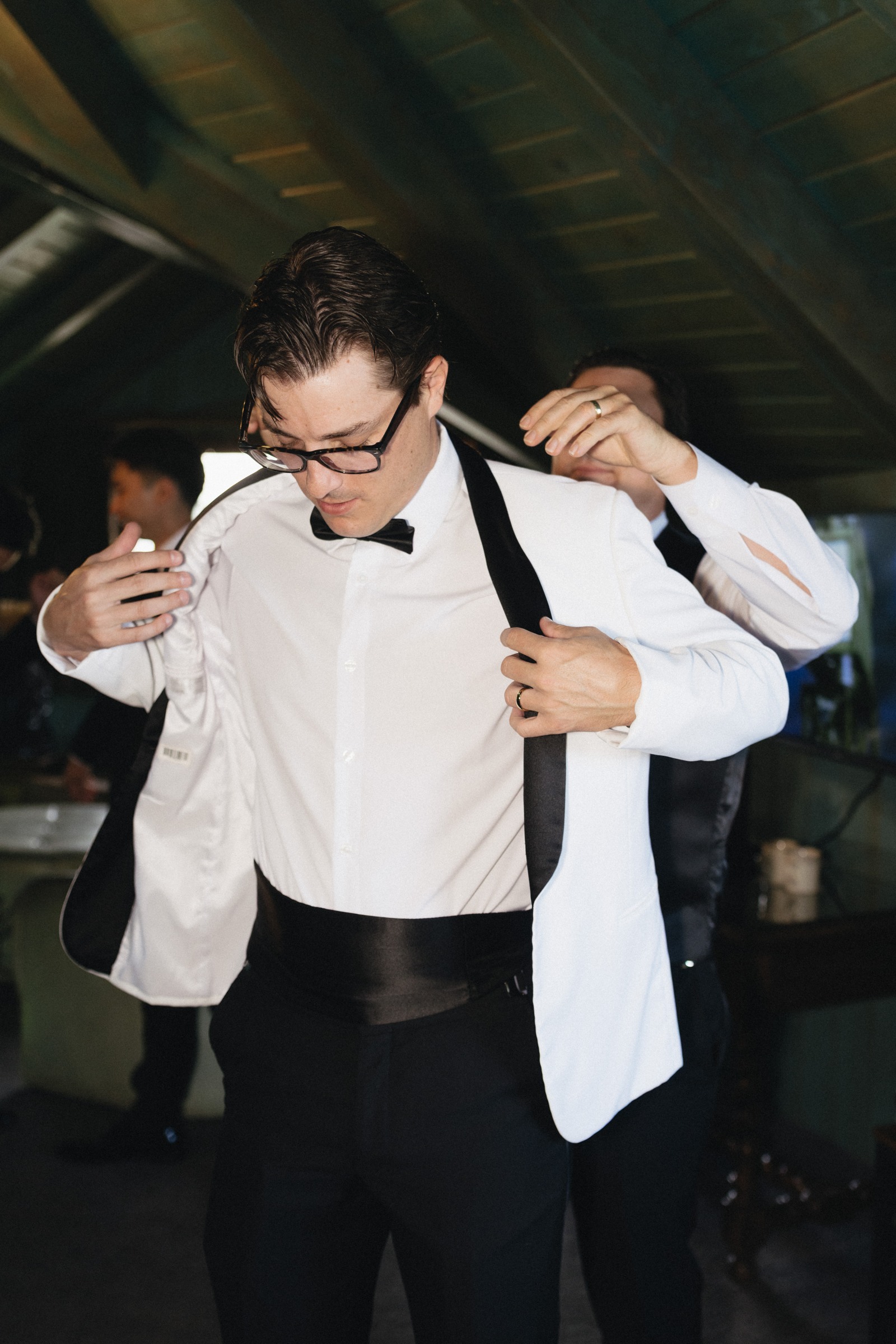 The groom getting ready in his white dinner jacket