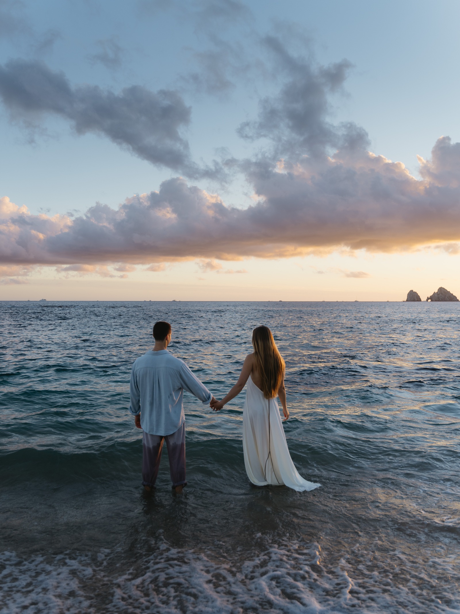 Holding hands in the sea at sunset