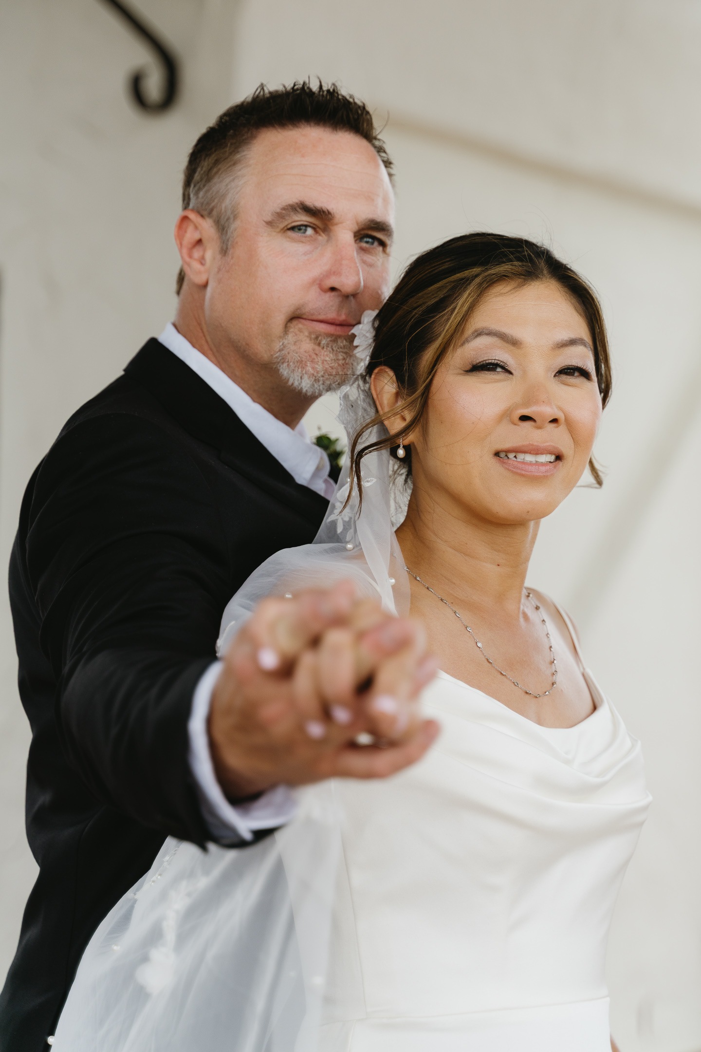 The couple holding hands beneath the courthouse arches