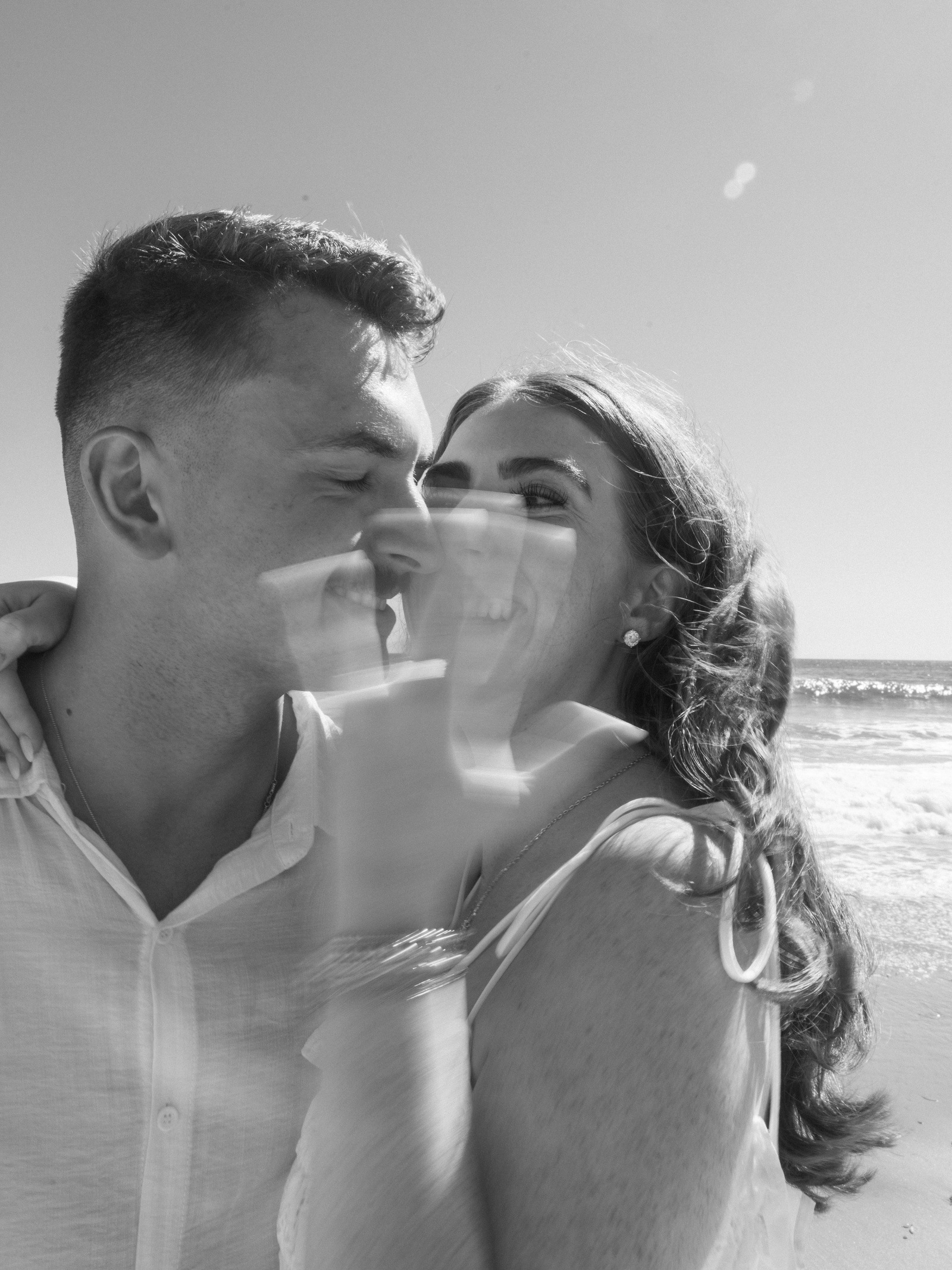 A newly engaged couple smiling together in black and white