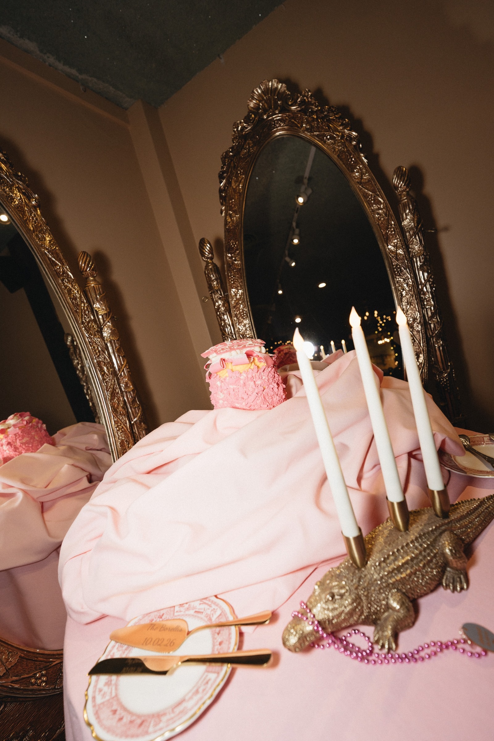 Pink wedding cake, candles and antique gold mirrors