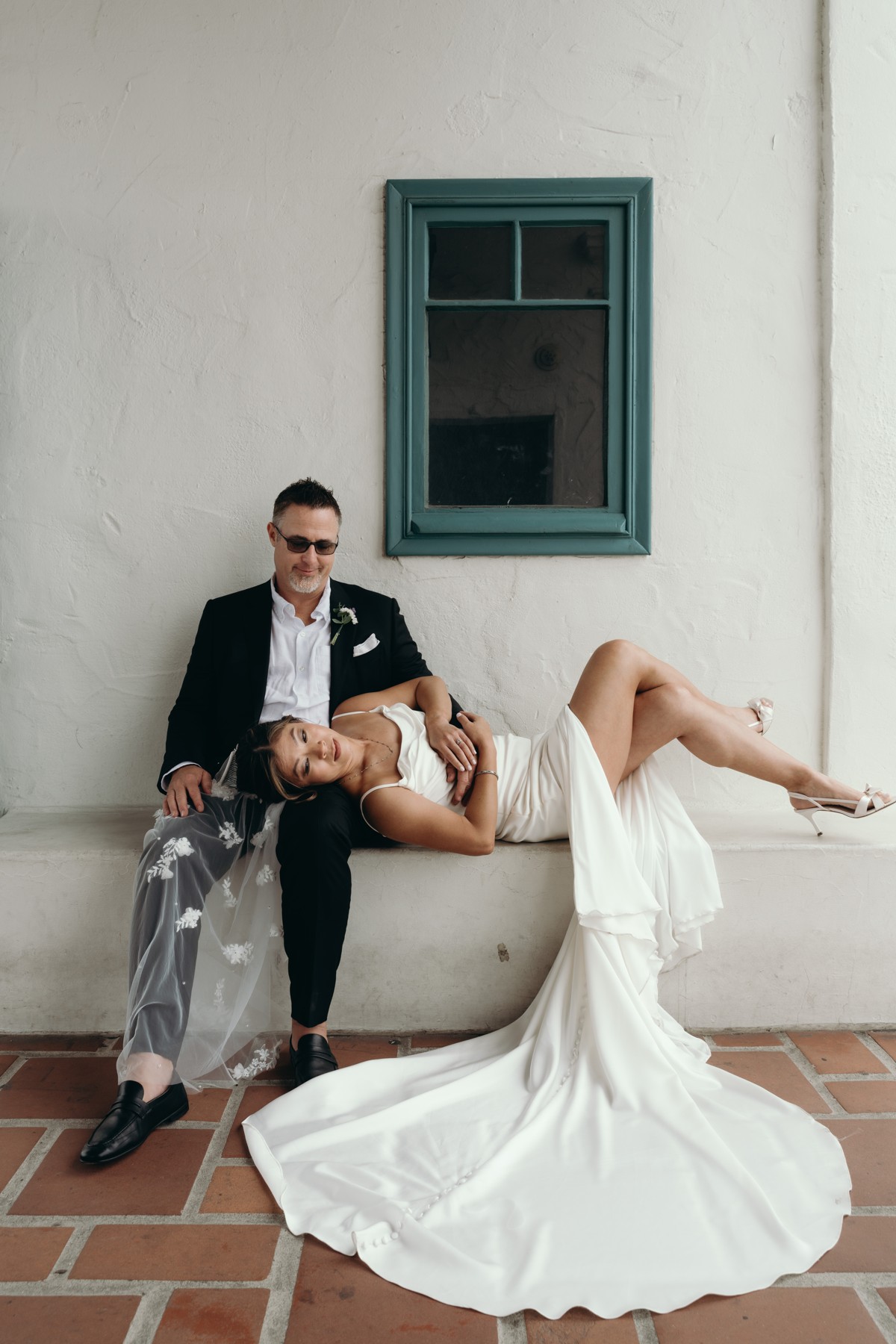 A couple relaxing together against a white courthouse wall