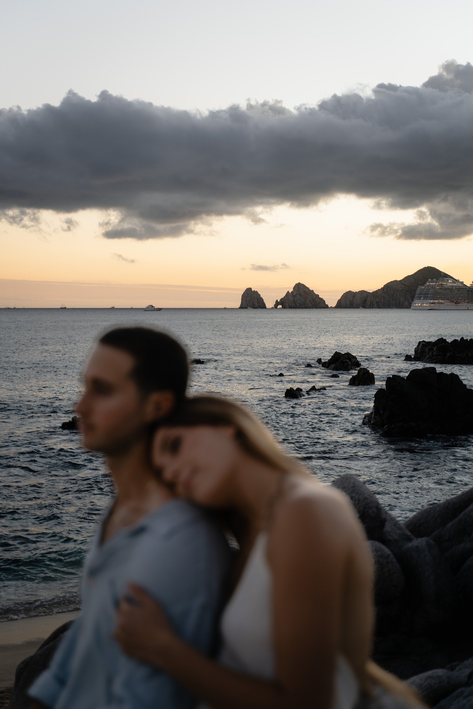 A couple embracing beside the ocean at sunset